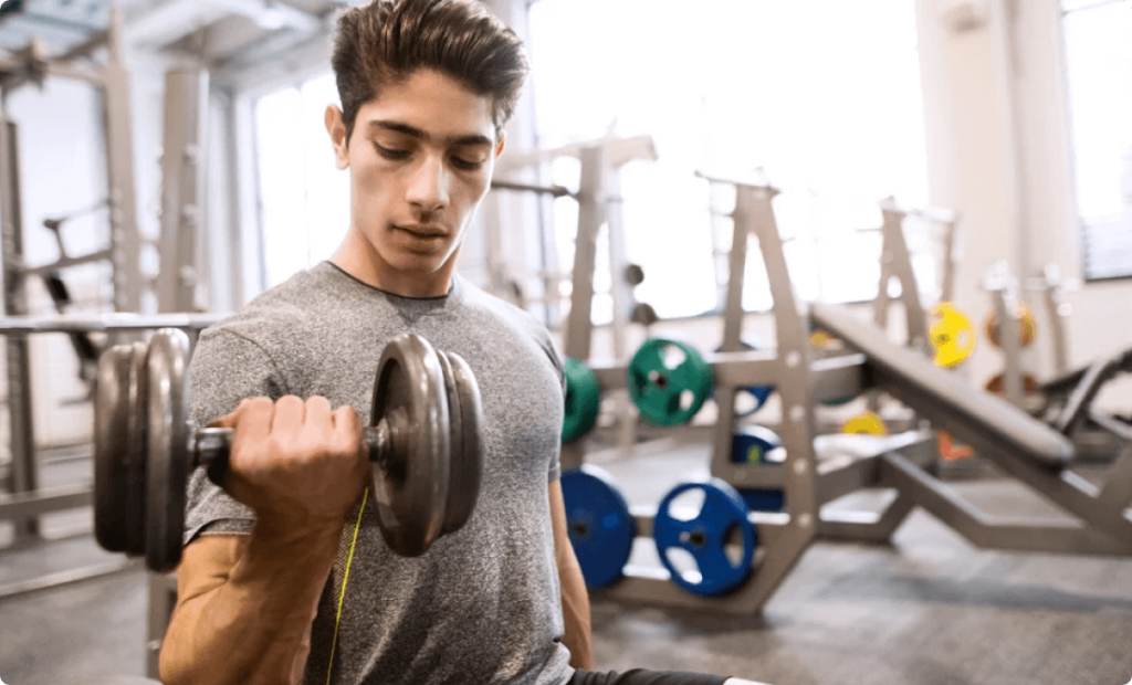 A body builder training in a gym and holding a dumbbell