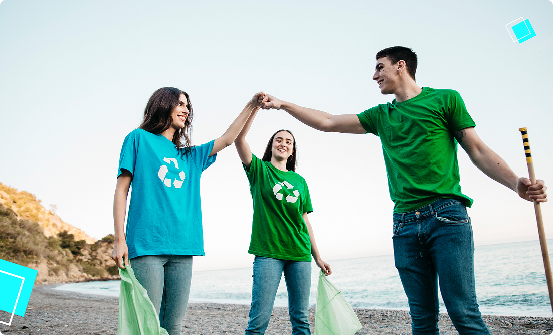 Teens in recycling shirts high-five while volunteering for a beach clean-up, promoting active community involvement over summer.