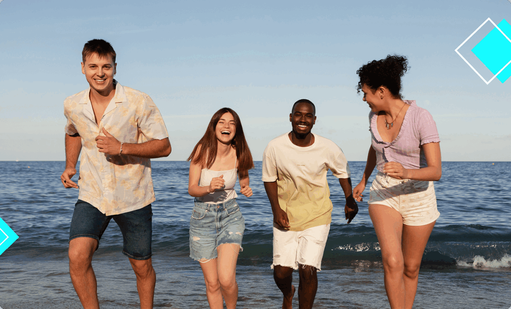 Group of diverse young adults running and laughing along the beach during summer break, promoting a healthy, active lifestyle with Vision Elite Training.