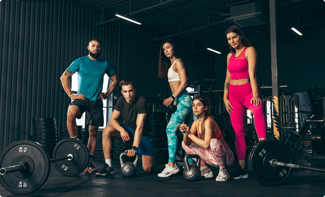 A group of five fit individuals posing confidently with weights and kettlebells in a modern gym, representing strength and team spirit at Vision Elite Training.